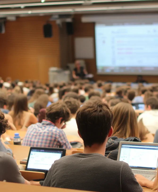 Lots of students in a lecture hall taking notes and on laptops