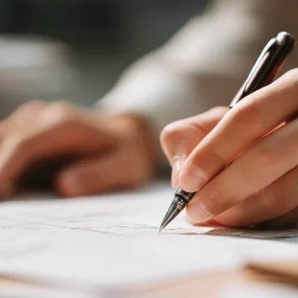 A hand holds a pen on paper