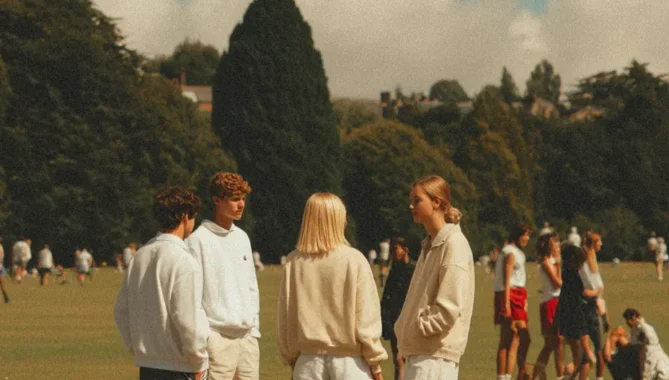 A lively sunlit scene of students outside gathering in British school grounds
