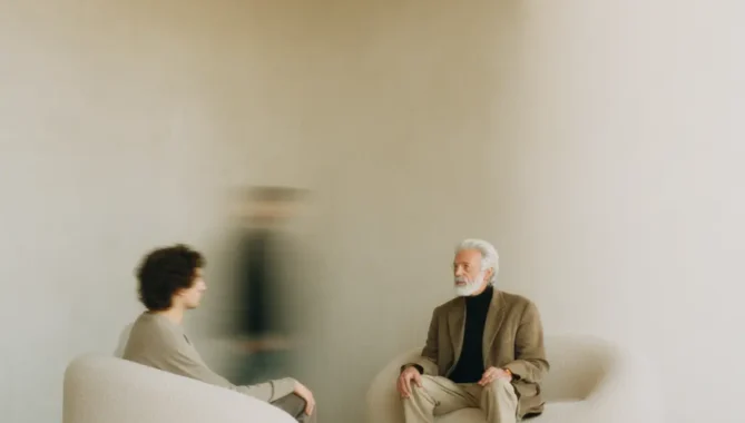 Older gentleman and student sat in a minimalist, modern Scandinavian interior