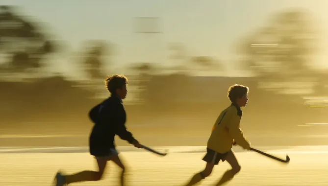 Close up of two kids in motion whilst playing field hockey