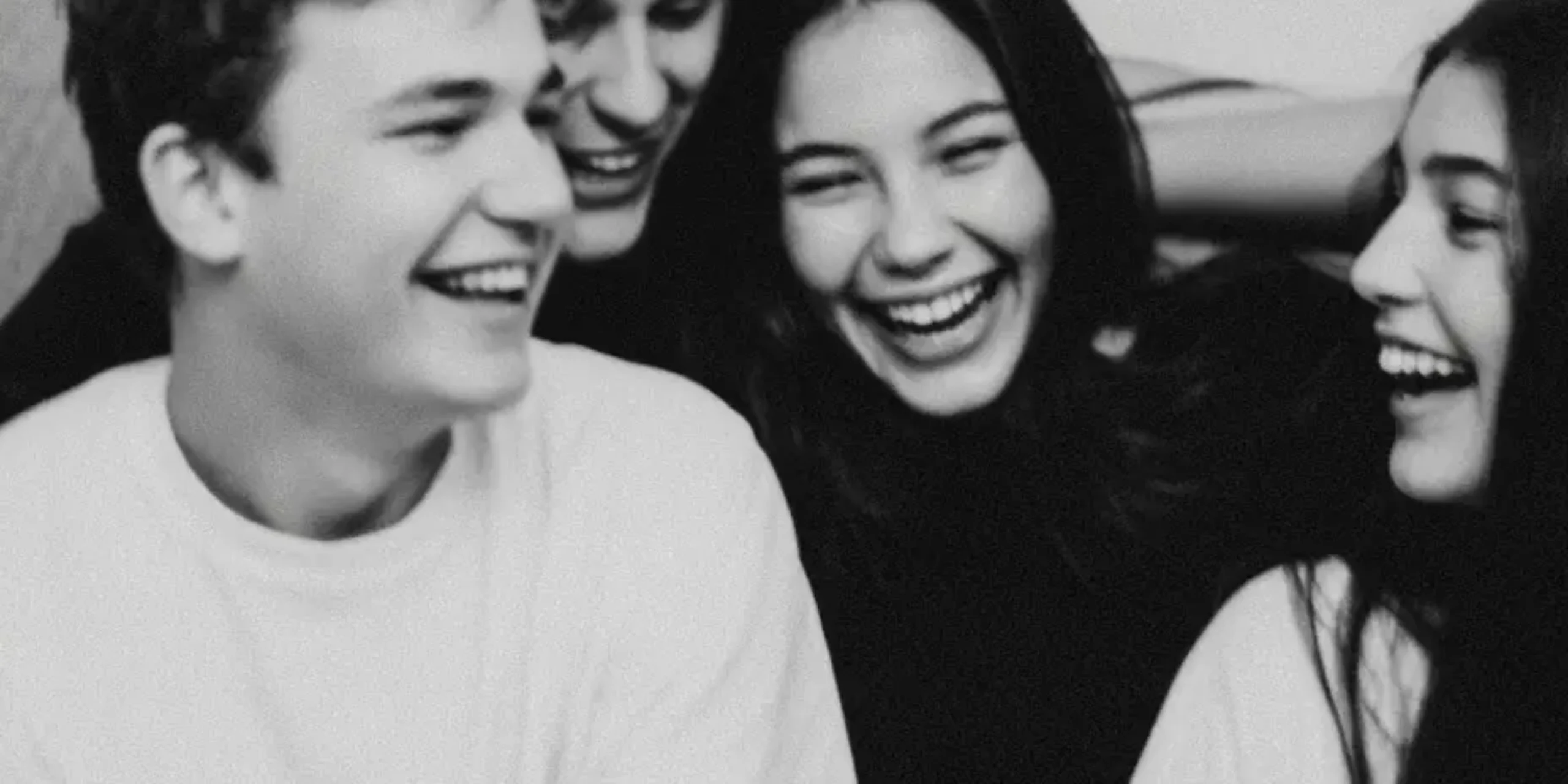 Group of teens sat on a sofa laughing and having a great time