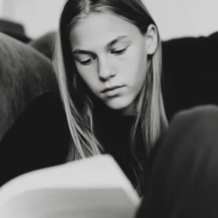 Teenager reading at home, black and white candid photography