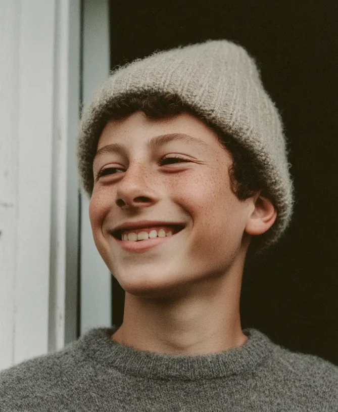 Happy younger child in a beanie with a grey jumper