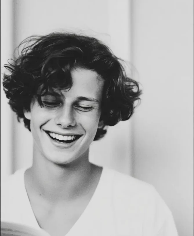 Oxbridge student smiling whilst reading from a book