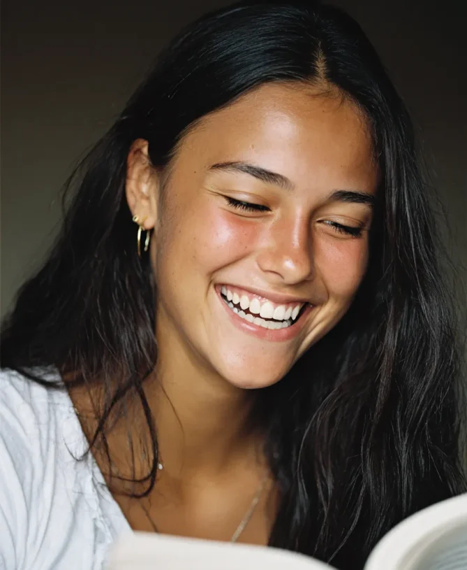 Happy teenage brunette girl reading book