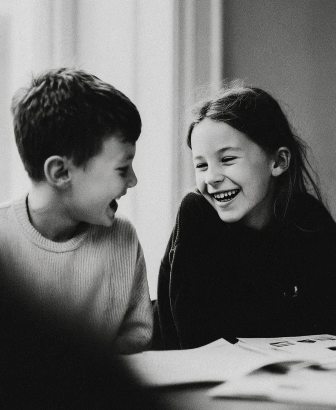 Candid moment of two young children receiving private tutoring laughing together