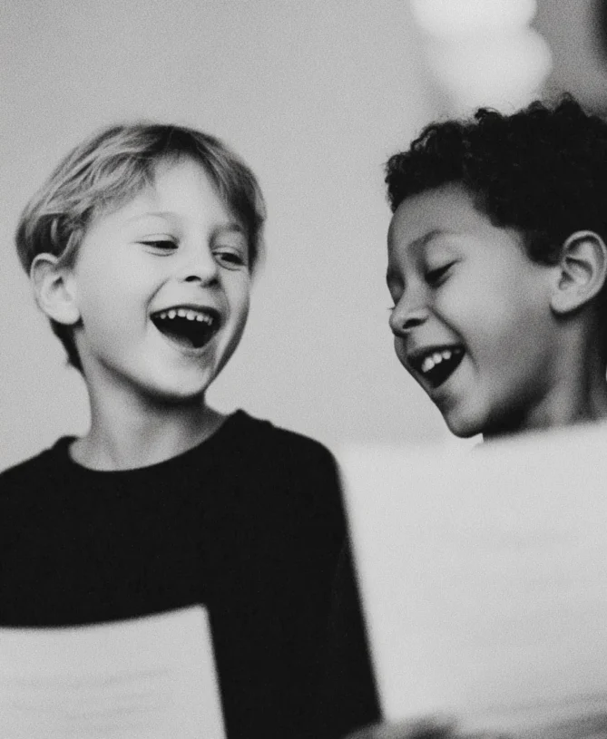 Candid moment of two young children laughing together as they hold paper document
