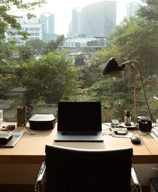 Cinematic looking photograph of a laptop and desk overlooking greenery in Asian cityscape