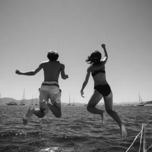 Two teens jumping off boat into sea