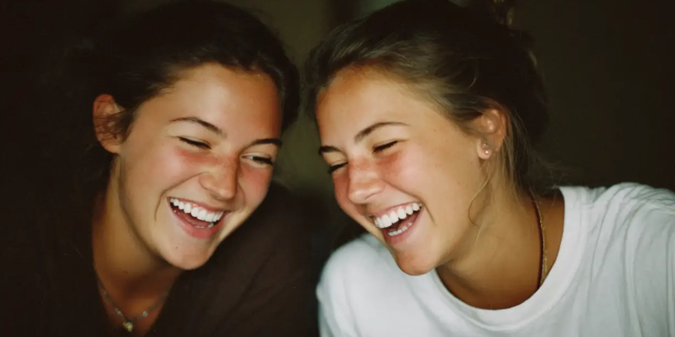 Two teenage friends laughing together over a book