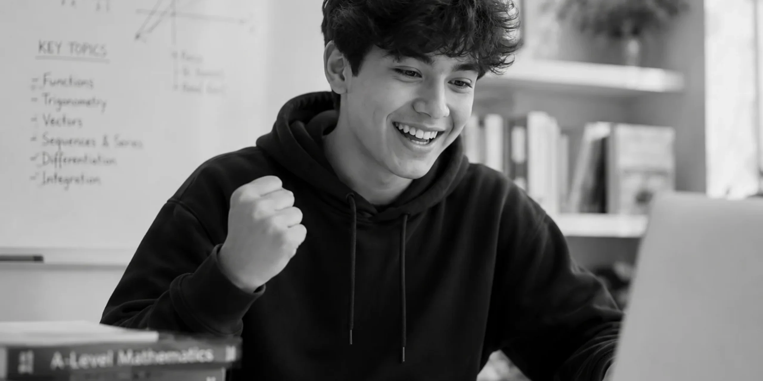 Excited student celebrating while studying online in a black-and-white academic setting.