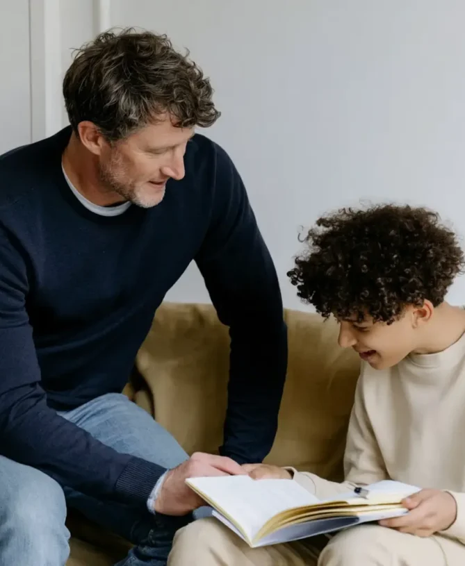 Tutor and student on chair reading over a book