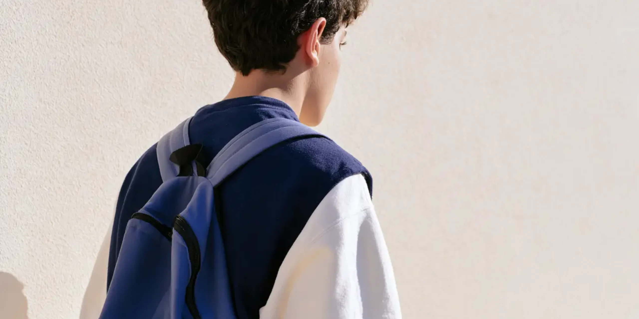 Teen with backpack, photograph taken from behind